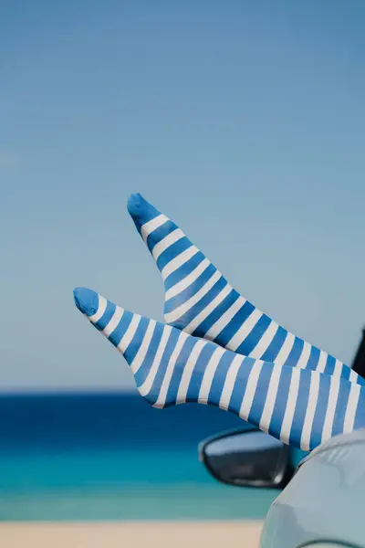 性感女人的腿穿着带条纹的长袜 面对蓝色的大海和天空 暑假短假A 图库图片