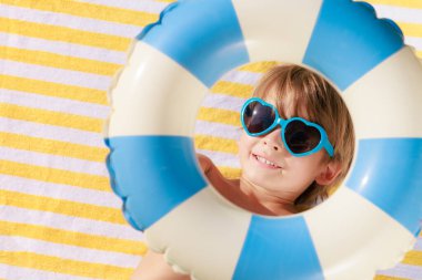 Mutlu çocuk plaj havlusunda yatıyor. Yaz tatilindeki komik çocuk. Çocuk yaz tatilinde eğleniyor. Üst görünüm portresi