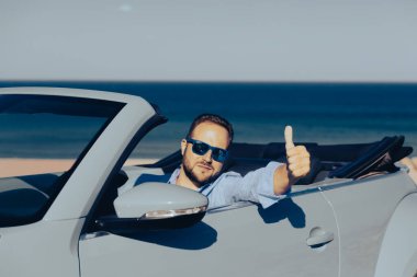 Bir plajda başarılı genç iş adamı. Cabriolet klasik arabada oturan adam. Yaz tatil ve seyahat kavramı.