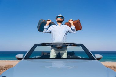 Bir plajda başarılı genç iş adamı. Cabriolet klasik arabada ayakta adam. Yaz tatil ve seyahat kavramı.
