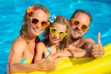 Mutlu bir aile yaz tatile eğleniyor. Baba, anne ve yüzme havuzunda oynayan çocuk. Etkin sağlıklı yaşam konsepti