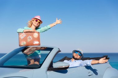 Mutlu çift deniz yoluyla araba ile seyahat ediyor. Mavi Cabriolet 'le eğlenen genç adam ve kadın. Yaz tatili kavramı