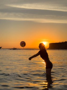 Plajda voleybol oynayan genç kızın silueti. Yaz tatilleri konsepti
