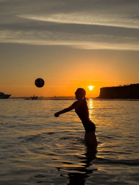 Plajda voleybol oynayan genç kızın silueti. Yaz tatilleri konsepti
