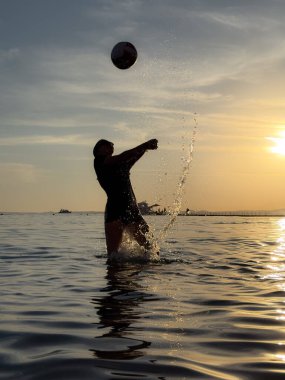 Plajda voleybol oynayan genç kızın silueti. Yaz tatilleri konsepti