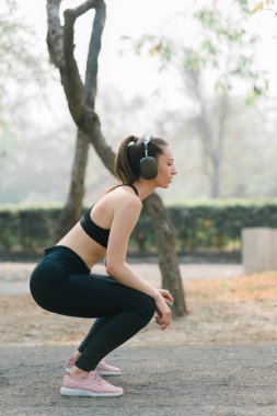 Görüntü, koşmak için giyinmiş genç bir kadını halka açık parkın patikalarına girmeden önce esnediğini gösteriyor.