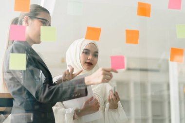 Yaratıcı bir beyin fırtınası sırasında, iş dünyası liderleri bir toplantı odasında toplanır, fikirlerini değiştirmek ve geliştirmek için yapışkan notlar kullanırlar.