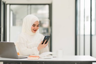 Başörtüsü takan güzel Müslüman iş kadını bilgisayarının başında özenle çalışıyor. İşine bağlılığını ve profesyonelliğini gösteriyor.