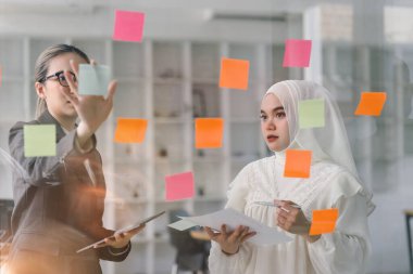 Bir yönetim kurulundaki yaratıcı çeşitlilik beyin fırtınası sırasında iş adamları ve Müslüman meslektaşları fikirlerini paylaşmak ve geliştirmek için yapışkan notlar kullanıyorlar.