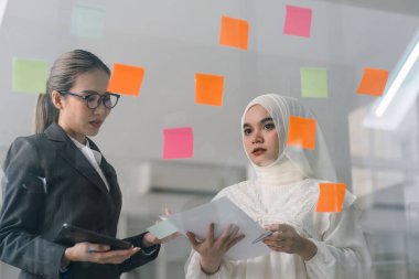 Bir yönetim kurulundaki yaratıcı çeşitlilik beyin fırtınası sırasında iş adamları ve Müslüman meslektaşları fikirlerini paylaşmak ve geliştirmek için yapışkan notlar kullanıyorlar.