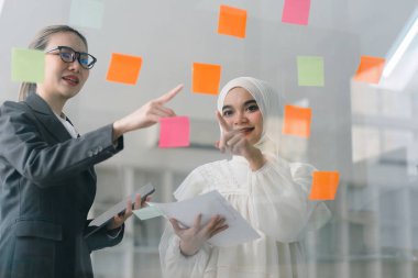Bir yönetim kurulundaki yaratıcı çeşitlilik beyin fırtınası sırasında iş adamları ve Müslüman meslektaşları fikirlerini paylaşmak ve geliştirmek için yapışkan notlar kullanıyorlar.