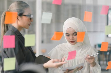 Bir yönetim kurulundaki yaratıcı çeşitlilik beyin fırtınası sırasında iş adamları ve Müslüman meslektaşları fikirlerini paylaşmak ve geliştirmek için yapışkan notlar kullanıyorlar.