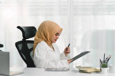 Başörtüsü takan güzel bir Müslüman iş kadını özenle bilgisayarının başında çalışıyor.