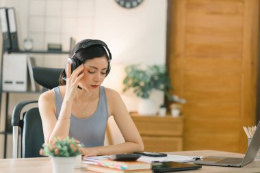 Stresli bir iş kadını evde çalışırken bunalmış, yorgun ve endişeli görünüyor.