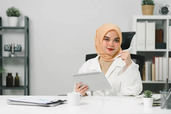 ヒジャーブを身に着けている美しいイスラム教徒の実業家が彼女のコンピュータで熱心に働いています — ストック写真