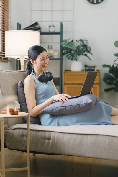 Happy young businesswoman is shown working on a laptop computer in her home office. The image represents the concept of working from home