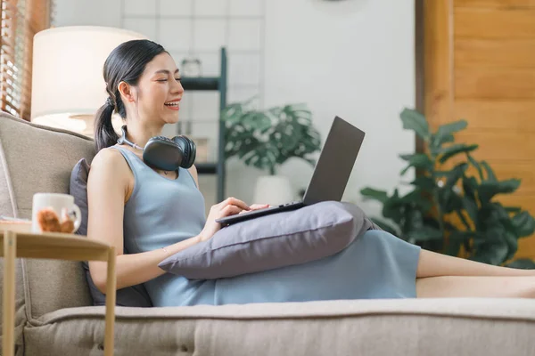 Happy young businesswoman is shown working on a laptop computer in her home office. The image represents the concept of working from home