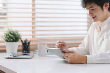 Gülümseyen genç milenyum işadamı dijital tablet bir bilgisayar tutuyor ve kullanıyor.