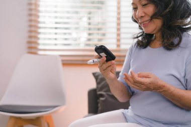 Yaşlı bir kadının elinde kan şekeri seviyesini glukometreyle tek başına kontrol ediyor.