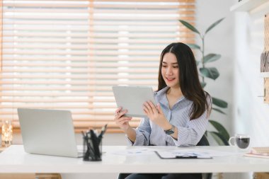 Görüntü, evinde çalışan neşeli genç bir iş kadınını gösteriyor. Uzaktan çalışma kavramını sembolize ediyor.