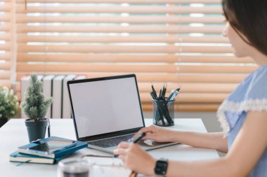 Ev ofisinin rahat bilgisayarında beyaz ekranda grafik montaj dizüstü bilgisayarı üzerinde çalışan bir kadının elleri yakın plan.