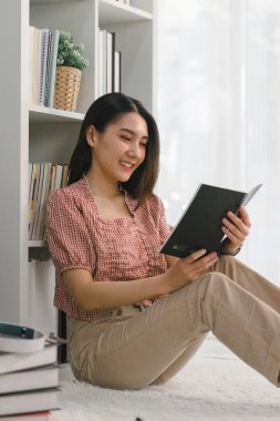 Mutlu genç bayan yerde kitap okuyarak rahatlıyor.