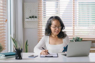 Gözlük takan, bilgisayarında çalışan, evinde defter ve kalemle mutlu bir son sınıf girişimcisi.