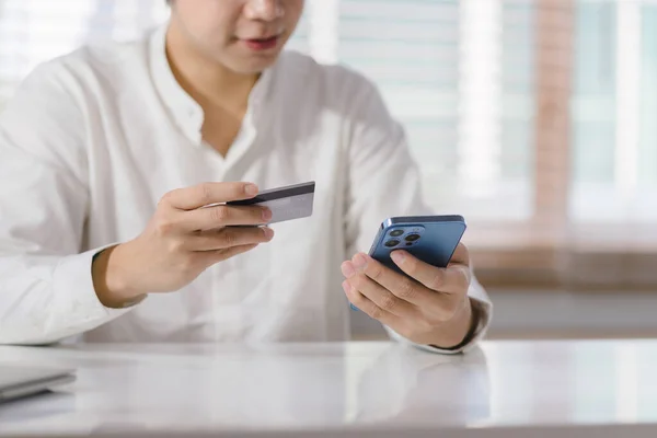 stock image Cropped shot of millennial man is paying with a credit card online while placing orders via mobile internet