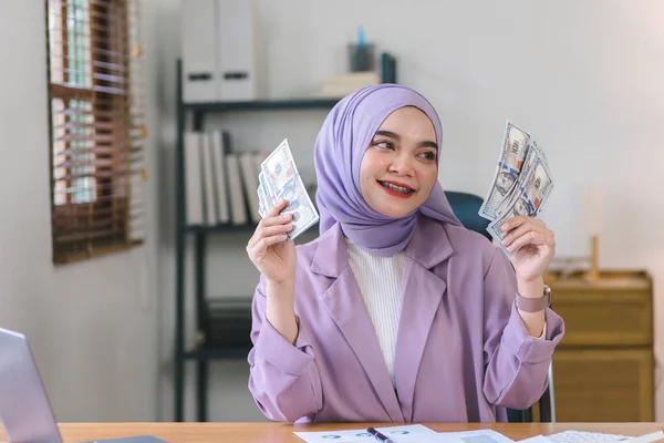 手に米ドルお金 美しいイスラム教徒のビジネスマン女性身に着けています紫色のヒジャーブ彼女の手にたくさんのお金を示しています — ストック写真