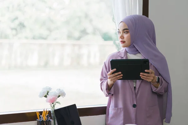 一个美丽的穆斯林千年亚洲女商人头戴紫色头巾在自家办公室远程办公的画像 — 图库照片