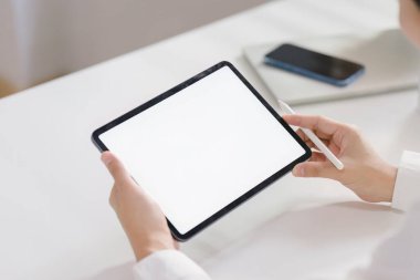 Dikiz aynasından bakıldığında, bir işadamının ofis masasında otururken elinde beyaz ekran dijital tablet bilgisayar tutarken ve kullanırken görülüyor.