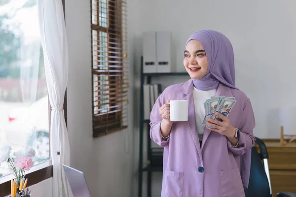 手に米ドルお金 美しいイスラム教徒のビジネスマン女性身に着けています紫色のヒジャーブ彼女の手にたくさんのお金を示しています — ストック写真