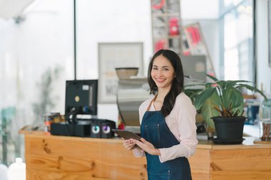 Gülümseyen, genç, güzel bir Asyalı kadın baristanın portresi. Bir kafede çalışırken önlük takıyor.