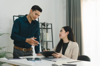 Girişim milenyum iş arkadaşları, bir toplantı odasında dijital tabletle maliyet grafiğini analiz etmek için birlikte çalışıyorlar.