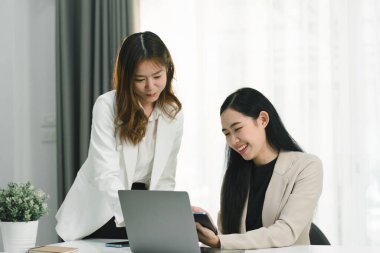 İki profesyonel Asyalı girişimci iş adamı bir konferans odasında değerlendirme verilerini tartışıyor, büyümeye odaklanıyor ve bir mali hesap grafiğine işaret ediyorlar,