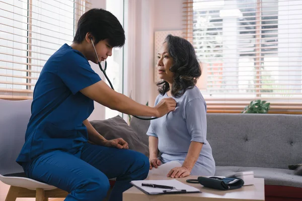 stock image Young Asian male nurse, assisted living in-home carer, or doctor visiting an old senior citizen at home to talk about result follow-up checklist, healthcare advice, or prescription