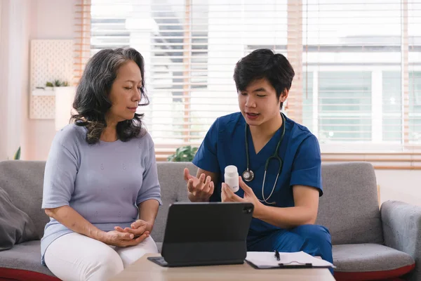 Health visitor and a senior woman with tablet during home visit. Elderly healthcare and Home health care service concept.