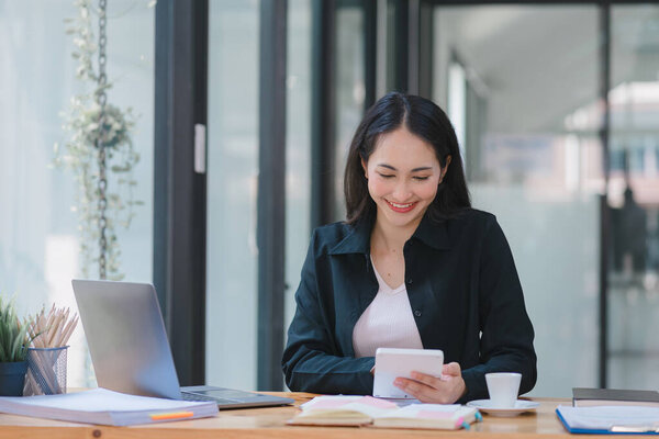 A businesswoman is working at her desk, using a calculator to perform calculations. Finance and accounting concept