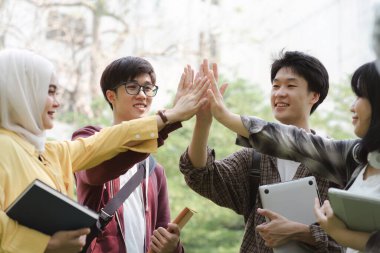 Çeşitli, çok ırklı bir grup genç, bir binanın dışında dururken ellerini üst üste koymaktan mutluluk duyarlar. Bu bir birlik, eğlence, ilişki ve gençlik kültürünü temsil ediyor.