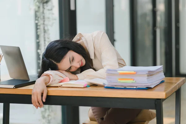 Stock image The tired millennial Asian businesswoman is feeling sleepy and bored from sitting at her desk for a long time, indicating a hard working day where she is overloaded with work