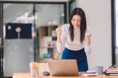 Mutlu ve heyecanlı, Asyalı genç bir öğrenci ya da ofis çalışanı, bir online yarışmayı kazanma hedefine ulaşmasını ya da coşkuyla el kaldırarak e-posta yoluyla iyi haberler almasını kutluyor.