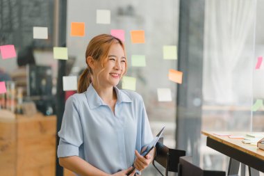 Profesyonel, güzel ve kendine güveni tam bir Asyalı kadın portresi. Arkadaş canlısı bir kişiliği var. Kapalı modern ofis geçmişine gülümsüyor. Olumlu insan duyguları