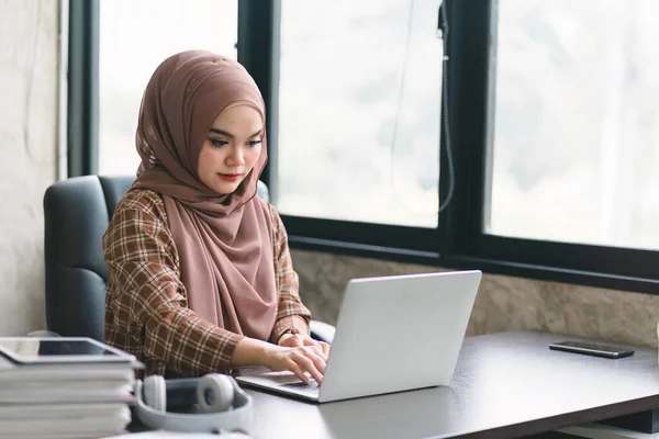 stock image A confident,beautiful, professional, millennial Muslim Asian businesswoman wearing a brown hijab is working remotely from modern office