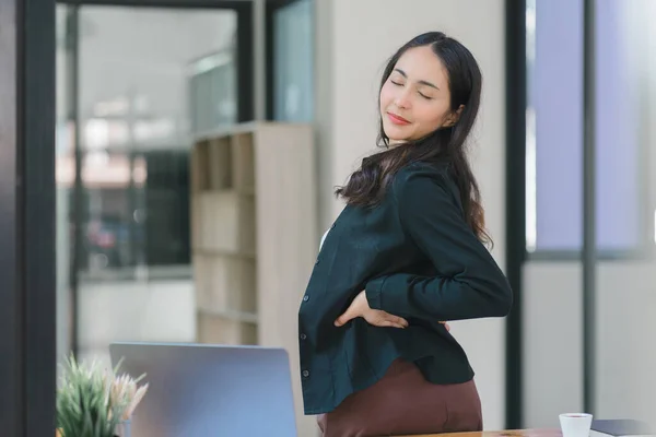 A businesswoman stretches lazily on her desk for relaxation while working in the office
