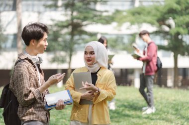 Üniversite öğrencilerinden oluşan çok ırklı bir grup, kampüsün yakınında dururken sınav için birlikte çalışıyorlar.