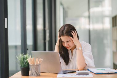 Tired frustrated young asian businesswoman feeling stressed holding head with hands, business problem failure concept