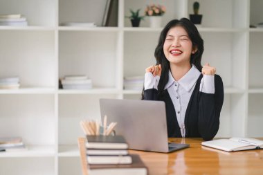 Başarıyı kutlayan genç bir iş kadınının portresi dizüstü bilgisayarın önünde kaldırılmış, yumrukları sıkılmış. Serbest Çalışan bir projeyi tamamladı.