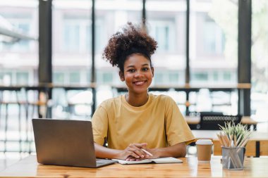 Genç Afrikalı Amerikalı bir kadın web sitesi kursunu izlerken not alıyor. Afro-Amerikalı öğrenci e-öğrenme yoluyla online çalışmak için konferansı dinliyor