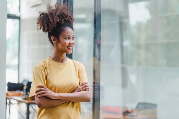 Stock image Friendly, cheerful, and attractive African American woman with afro hair standing with her hands crossed over her chest