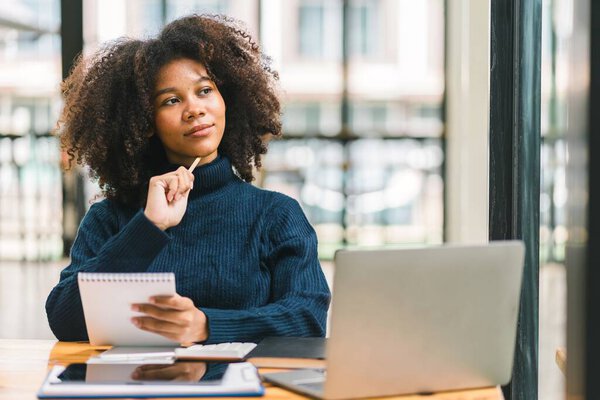 African American businesswoman or accountant with afro hair using a calculator, graphs, and charts to analyze market data, balance sheets, accounts, and net profits